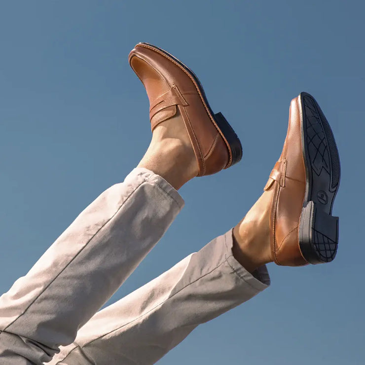 Man with his legs in the air showing off a stylish sandro moscoloni penny loafer stuart in tan